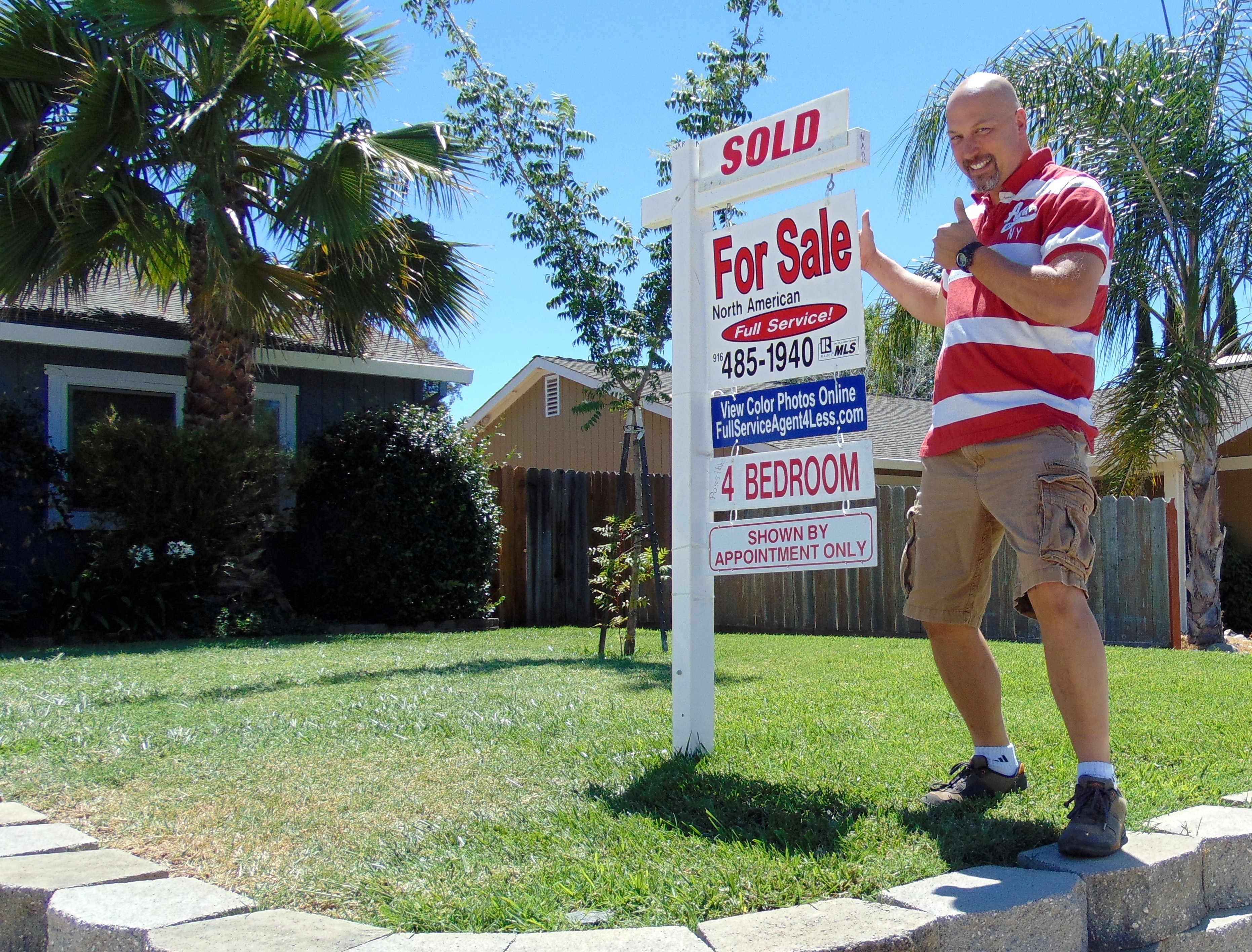 Photo of 1 of our Sellers with a Sold sign in front of their home.