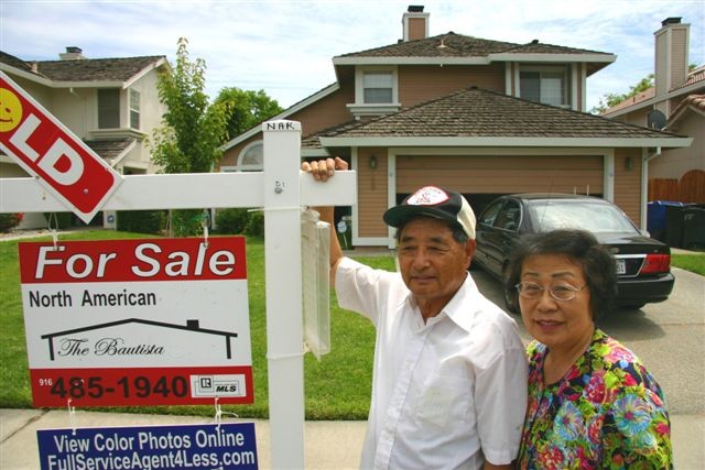 Photo of 1 of our Sellers with a Sold sign in front of their home.