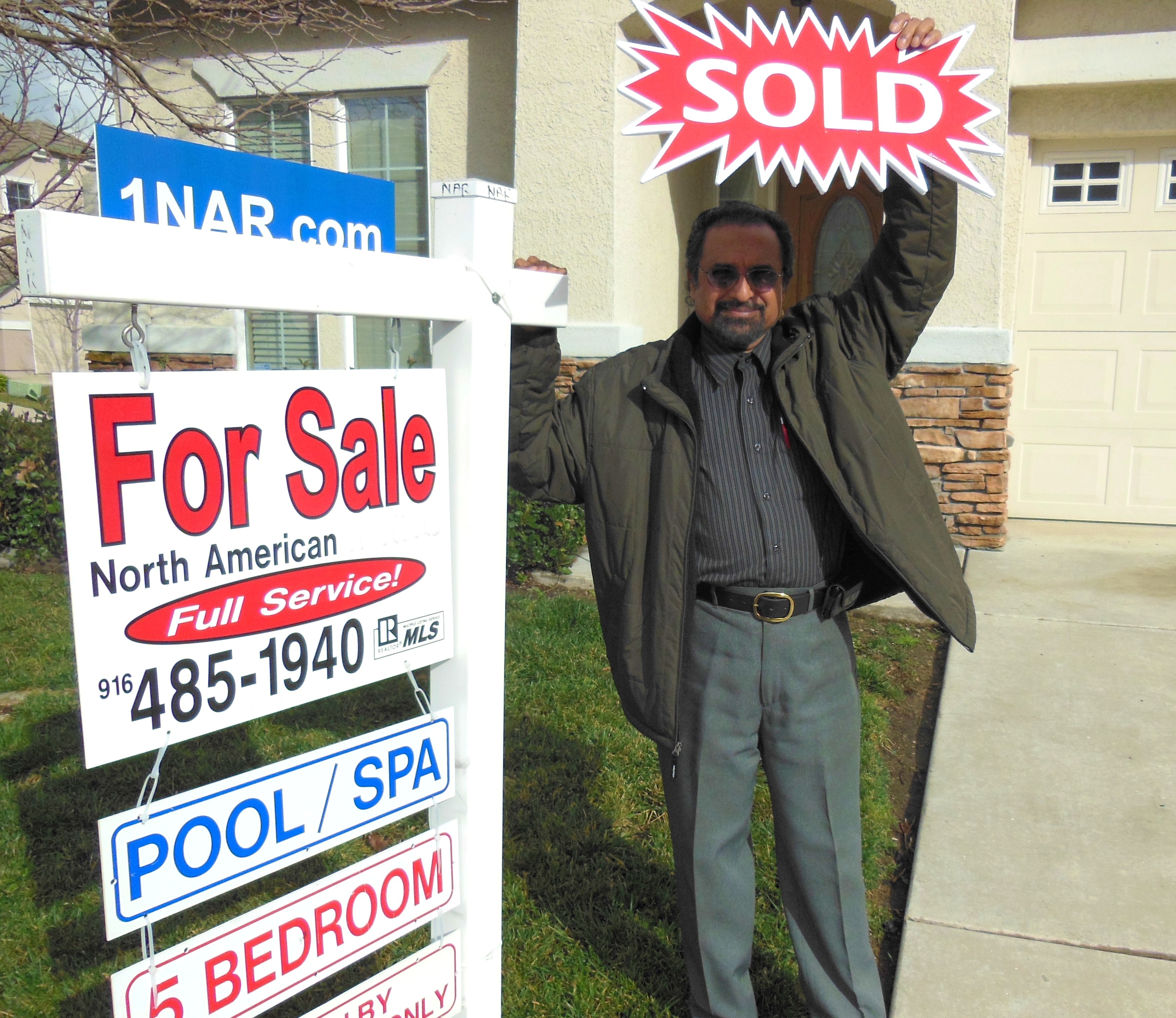 Photo of 1 of our Sellers with a Sold sign in front of their home.